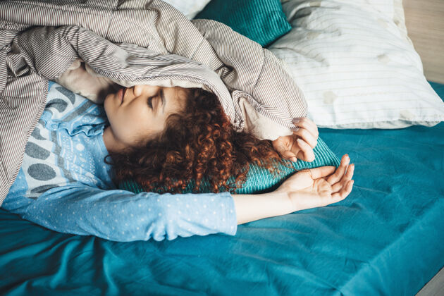 被子懒散的白种女人 卷发 蓝色睡衣 躺在被子里睡觉新鲜成人睡衣