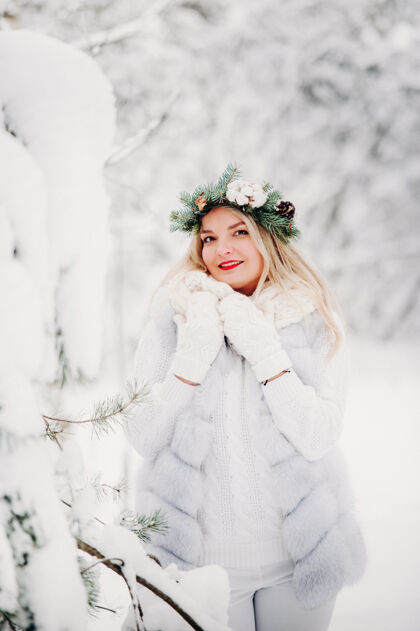 肖像一个穿着白衣服的女人在寒冷的冬天的照片森林女孩她头上戴着花圈在冰雪覆盖的冬季森林里风景生活方式雪