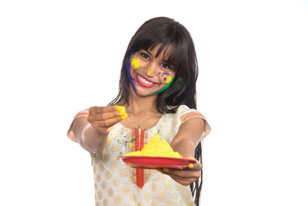 粉在胡里节之际 美丽的年轻女孩拿着盘子里的彩粉享受女性节日