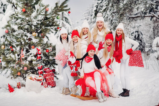优雅一大群手里拿着圣诞礼物的女孩站在冬天森林女孩穿着红白相间的衣服 带着圣诞礼物在雪林里大节日森林手套