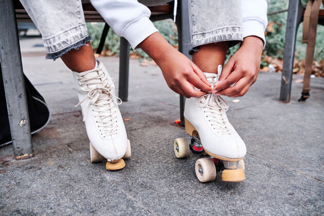 鞋一位女士在户外滑冰前系上溜冰鞋鞋带的特写镜头街道.城市和运动理念爱好户外女子