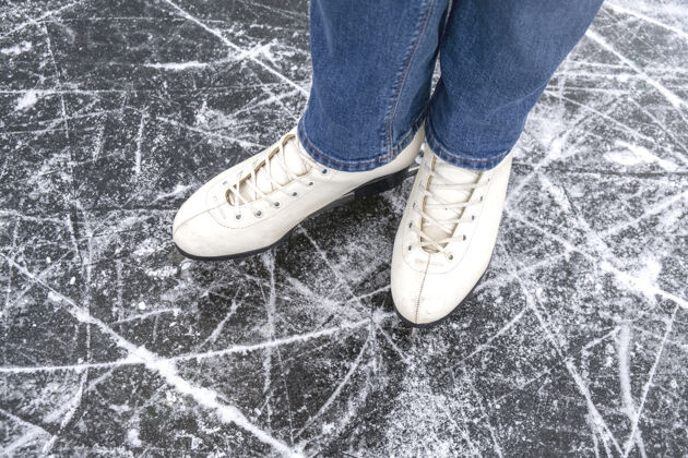 寒冷休闲的女人看在冰鞋和牛仔裤上冰宏俯视运动牛仔裤休闲
