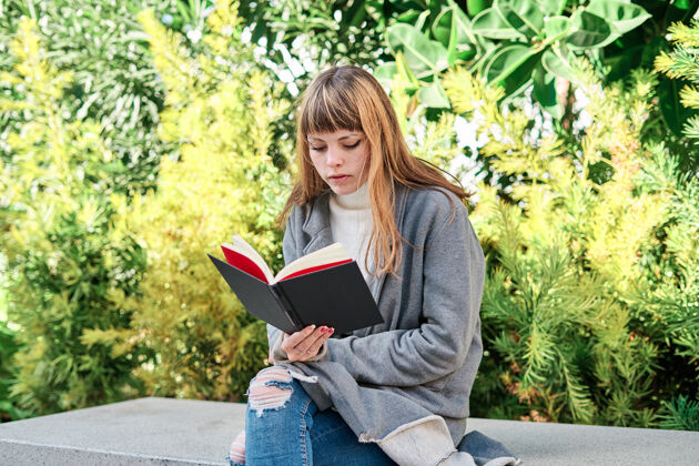 女人一个蓝眼睛的白人金发年轻女子在公园看书女性阅读金发