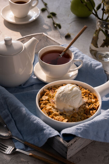 香草苹果碎与一勺香草冰淇淋和茶放在木桌上托盘早餐概念派面包屑传统