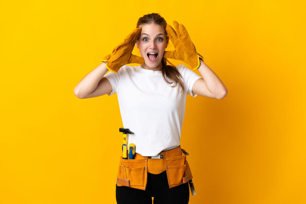 成人年轻的电工女士带着惊奇的表情隔离在黄色的地板上修理人害怕