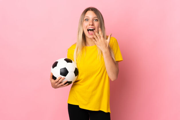 哇一个年轻的足球运动员 一个脸上带着惊讶表情的粉红色女人球员震惊欢呼