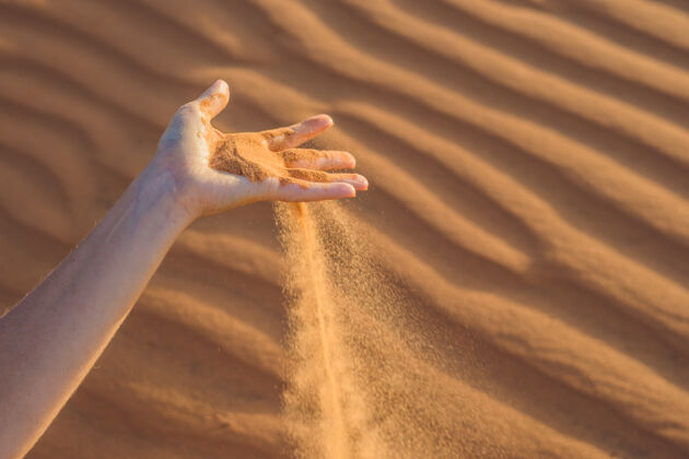 温柔沙漠里 沙子从一个女人的手上滑过干燥沙子失去