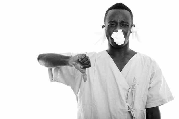 失望年轻的非洲男子作为医院的病人被隔离在白墙黑和白羽绒疾病人