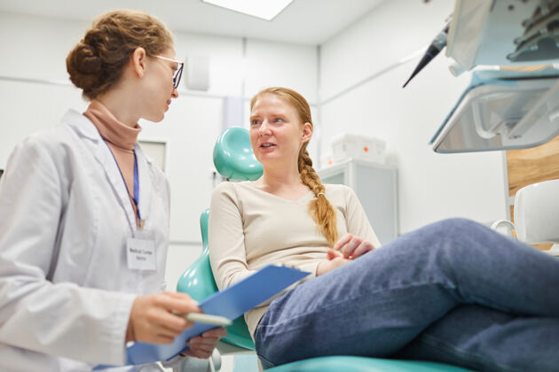 实验服女病人坐在牙科手术椅上 在诊所和牙医讨论医疗程序设备笑牙科