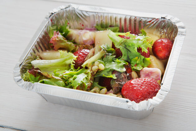 送货健康的午餐和饮食概念外卖食物松子 豌豆和草莓沙拉与生菜在白木蔬菜美食晚餐