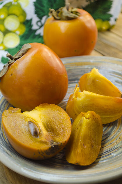 食物成熟的柿子放在木桌上的盘子里产品异国情调盘子