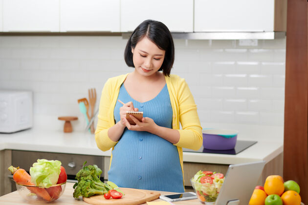 中国孕妇拿着笔记本写下食谱列表女人素食