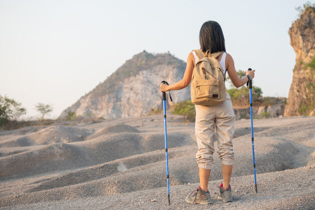 健康适合女性徒步旅行者与背包和杆站在洛基山脉眺望山谷和山峰人徒步旅行者人