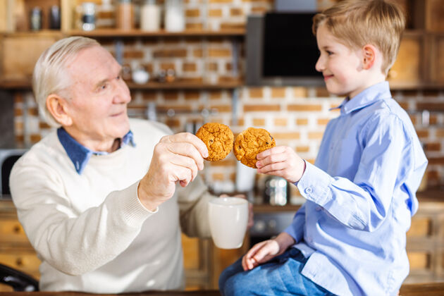 甜点可爱的小男孩在家休息时和爷爷一起吃自制糕点爸爸享受爷爷