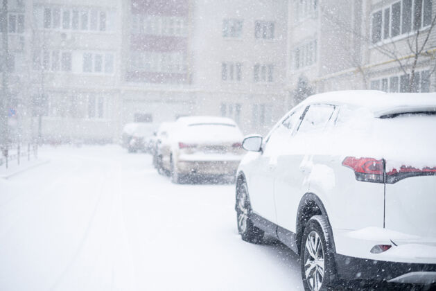 重冬天汽车被雪覆盖 外面有暴风雨交通城市住宅