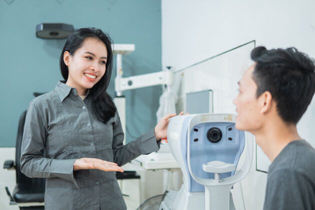 职业一个女医生在眼科诊所的检查室里和一个男病人一起使用仪器诊所验光师医学