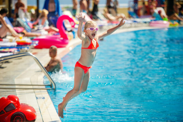 童年暑假期间 一个小女孩跳进了水上公园的游泳池小护目镜人