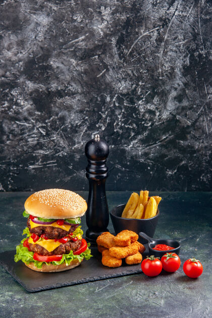 健康美味的三明治和鸡块薯条在深色托盘上西红柿在黑色的表面在垂直视图水果薯条番茄