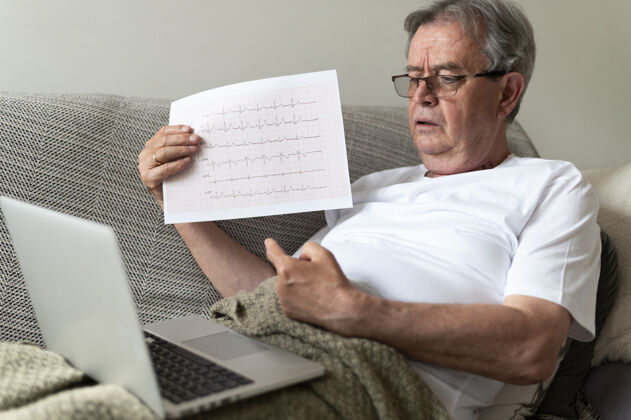 老年人躺在沙发上拿着笔记本电脑的中枪病人笔记本电脑医生援助