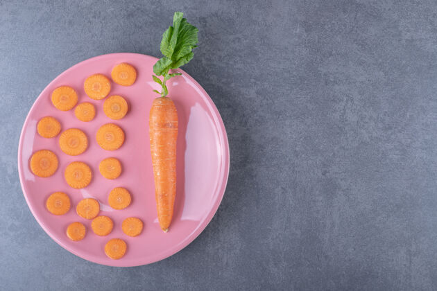 营养整个胡萝卜和切成片的胡萝卜放在盘子里 放在大理石表面上好吃的蔬菜农作物