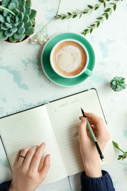 人桌上一杯咖啡的女人在笔记本上写字时间能源光