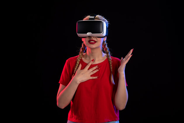 游戲年輕女性在黑暗視覺上玩虛擬現實的正面視圖帽子頭盔視覺