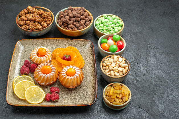 美味灰色空间上有糖果和坚果的美味蛋糕饼干晚餐水果