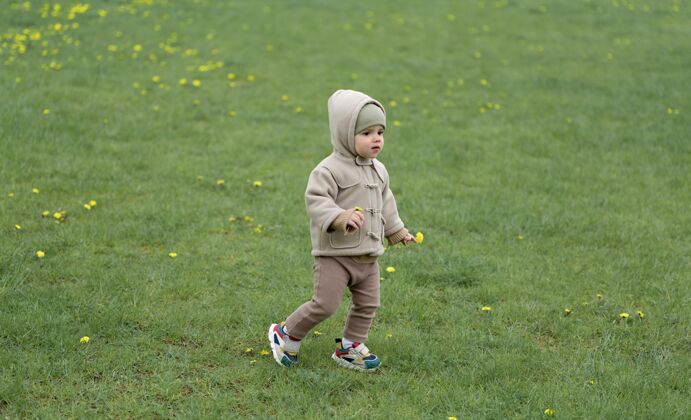 外面可爱的孩子在草地上散步小蹒跚学步家庭