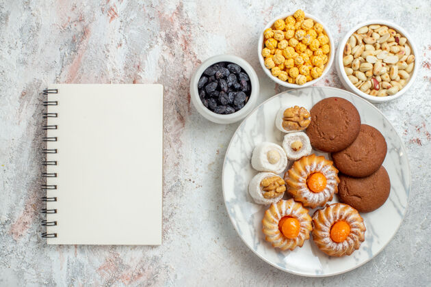 杯子俯瞰美味饼干 白色桌面上有糖果和坚果甜饼饼干坚果鸡蛋用餐咖啡