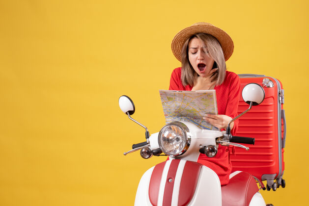 模型骑着轻便摩托车 拿着地图的红色手提箱的漂亮女人惊呆了红色自动装置摩托车