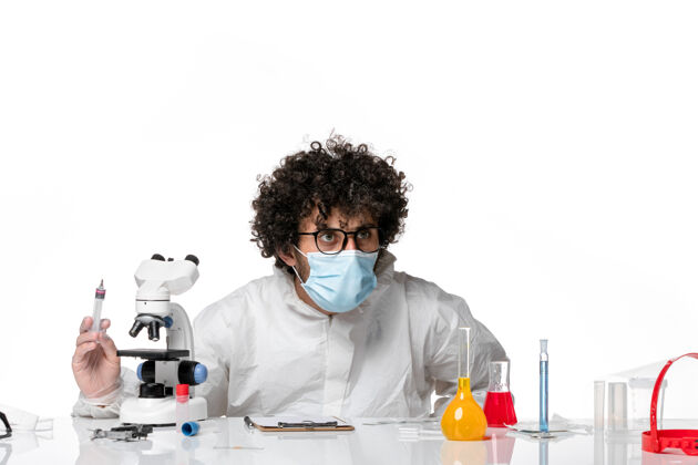 实验室正面图：男医生穿着防护服 戴着口罩 手拿针剂在白色皮肤上持有实验室外套专业