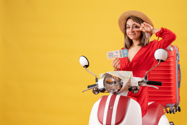 红色微笑着的年轻女士 穿着红色的衣服 骑着轻便摩托车 手里拿着机票微笑的年轻女士飞机坐