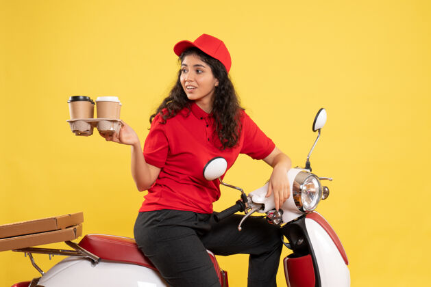 服务前视图骑自行车的女快递员拿着咖啡杯在黄色背景上工作服务工作女快递工作咖啡杯子人