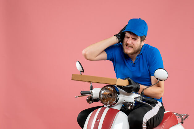 男信使正面图男性信使坐在自行车上 拿着粉红色的比萨饼盒持有送货盒子