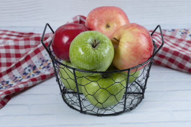 成熟红色和绿色的苹果放在金属黑色的篮子里 放在白色的背景上高质量的照片食物有机健康