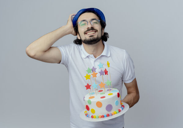 头一个戴着眼镜 戴着蓝帽子 拿着蛋糕 手放在头上 面带微笑的帅哥手眼镜蛋糕