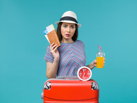 航行前景度假妇女手持浅蓝色背景上的机票和果汁远航度假海上旅行旅程女性举行女果汁
