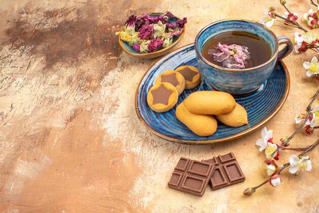 茶各种饼干的俯视图一杯茶和鲜花混色桌上的巧克力棒午餐盘子蔬菜
