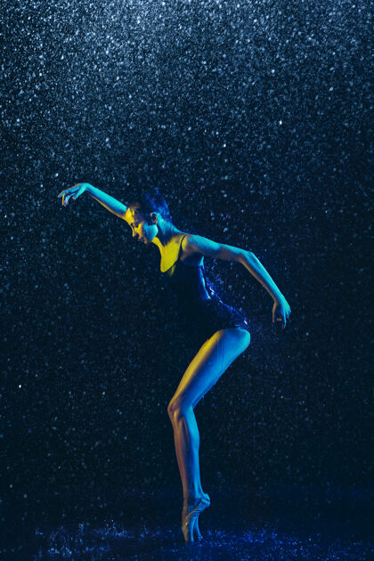 人两个年轻的女芭蕾舞演员在水滴下霓虹灯舞蹈赤脚