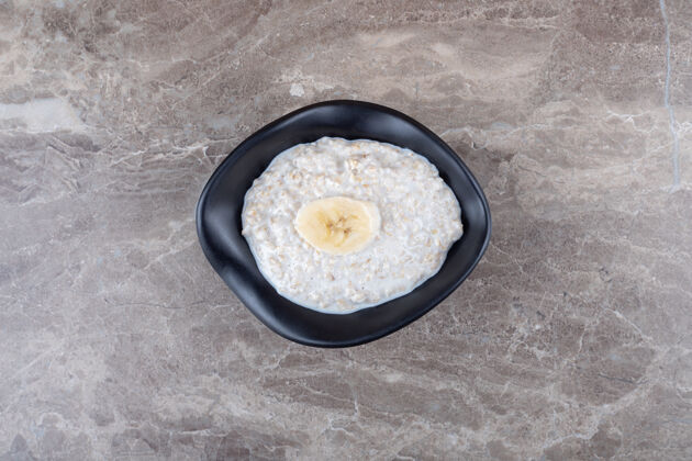 风味成熟的香蕉片放在一碗粥上 放在大理石表面切片美味配料