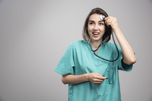 职业女医生带着听诊器在灰色背景上大笑高质量照片妇女工作成人