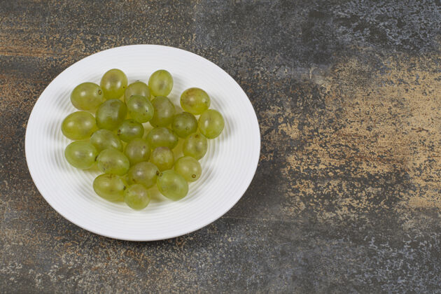 健康白盘子里放着新鲜的绿葡萄一串美味新鲜