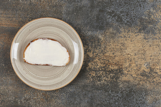 奶制品在陶瓷盘子上放一片烤面包和酸奶油切片面包小吃