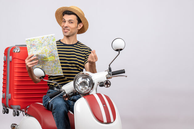 摩托车手持轻便摩托车的地图上戴着草帽的幸福青年的正视图帽子骑车辆