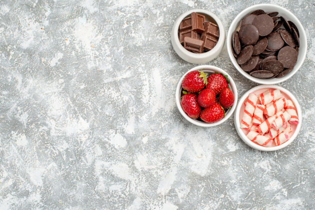 甜点在灰白色地面的右上角有草莓 糖果和巧克力的顶视图碗草莓新鲜健康