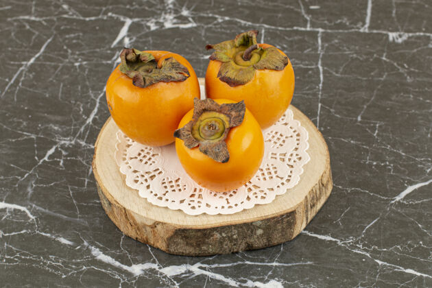 新鲜新鲜的三个柿子在木板上亚洲素食食谱