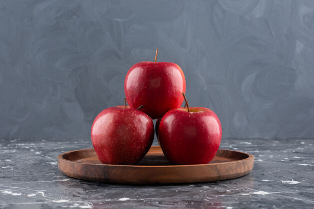 苹果红光闪闪的整个苹果放在木盘上食品红色水果