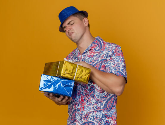 年轻人一个戴着蓝色帽子的年轻人拿着礼物盒 看着橙色的礼物盒派对蓝色帽子