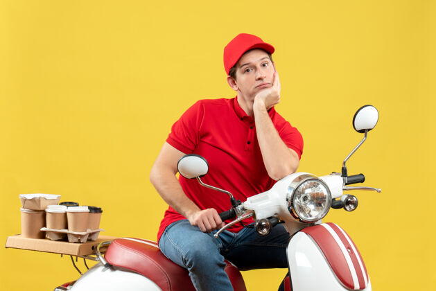 摩托车俯视图中的年轻人穿着红色上衣 戴着帽子 在黄色背景下沉思着传递着秩序深成年人车