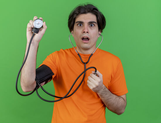 绿色惊讶的年轻病人测量自己的血压计隔离在绿色年轻男人血压计